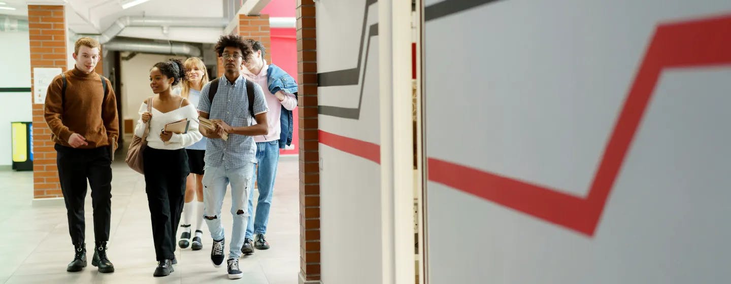A group of teenagers of mixed ethnic backgrounds in a corridor, heading to a classroom